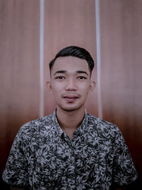 Portrait of young man standing against wall