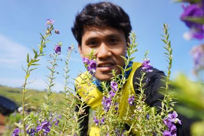 Portrait of smiling woman against purple flowering plants against sky