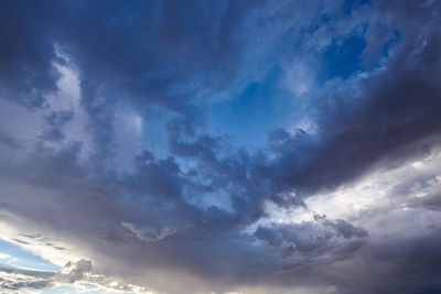 Low angle view of sunlight streaming through clouds