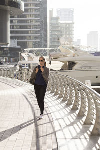 Full length of woman standing on promenade in city during sunny day