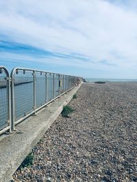 Walkway leading towards sea against sky