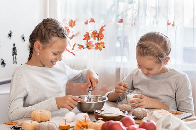 Two cute little girls sisters are preparing and kneading ginger dough for making cookies 