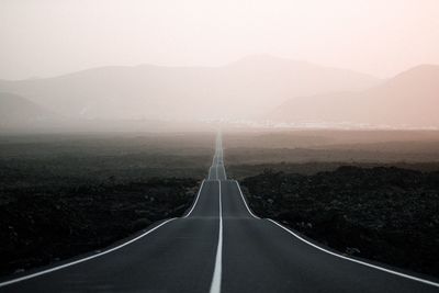 Empty road along landscape and mountains against sky