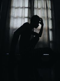 Silhouette of young man sitting at home