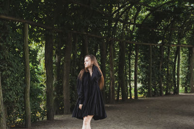 Beautiful young woman standing by plants outdoors