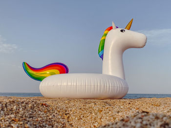 Multi colored toy on beach against sky