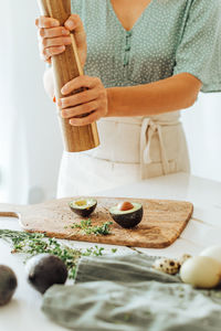 Woman holding wooden spice grinder seasoning avocado