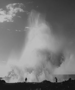 People standing on splashing sea waves