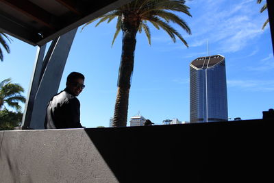 Low angle view of man standing by palm tree