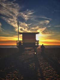 Silhouette people on beach against sky during sunset