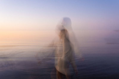 Side view of woman standing against sky during sunset