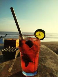 Glass of drink on table at beach