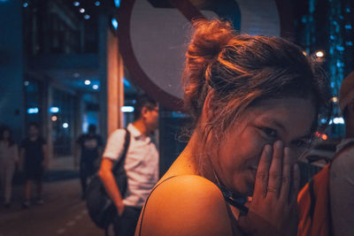 Close-up portrait of young woman in city at night