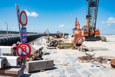 Road sign at construction site against sky