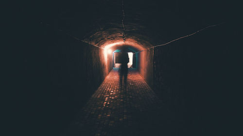 Rear view of man walking in tunnel