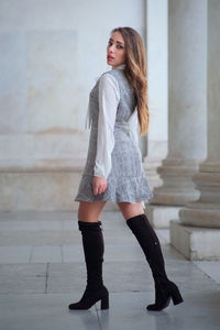 Full length portrait of woman standing against wall