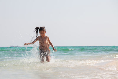 Man splashing water in sea against sky