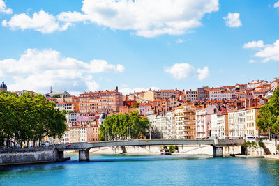 Town by river and buildings against sky