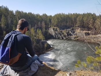 Rear view of man standing on riverbank against sky