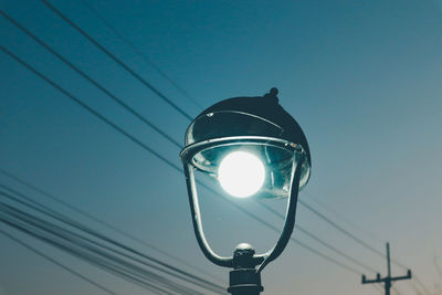 Low angle view of illuminated street light against blue sky