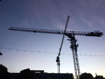 Low angle view of silhouette cranes against sky