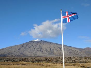 Icelandic flag with the famous snæfellsjökull mountain in the background on a fall afternoon.