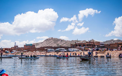 Boats moored at harbor by town against sky