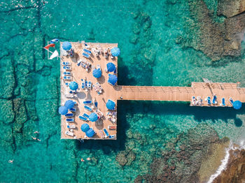 Drone view of lounge chairs and parasols on pier over sea