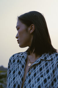 Portrait of young woman looking away against white background