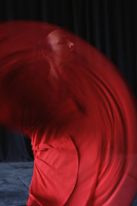 Young woman with makeup in red and black apparel performing traditional spanish dance while looking away