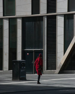 Rear view of woman walking on footpath against building