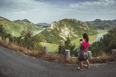 Rear view of woman standing on road against mountain