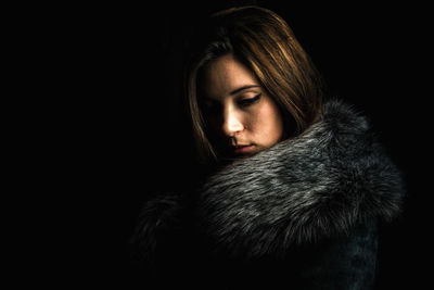 Portrait of young woman against black background