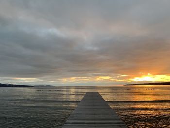 Pier over sea against sky during sunset