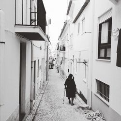 Rear view of person walking on footpath amidst houses