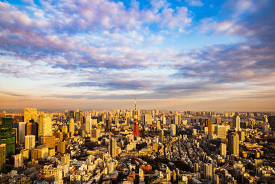 Aerial view of buildings in city against cloudy sky
