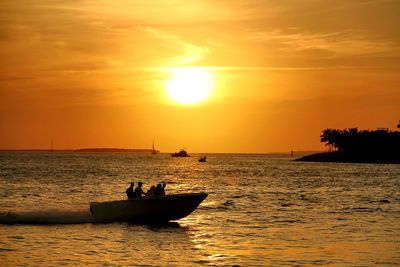 Silhouette speedboat in water against cloudy sky at sunset