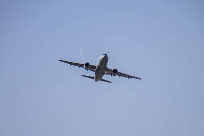 Low angle view of airplane against clear blue sky