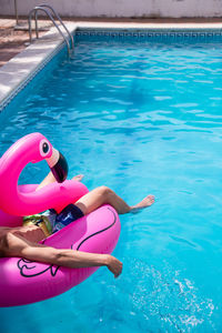 Low section of man relaxing in inflatable ring on swimming pool