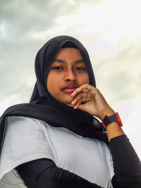 Portrait of a beautiful young woman against sky