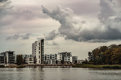 Buildings by river against sky in city