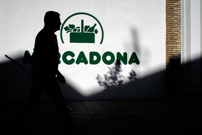 Side view of silhouette man standing by sign on wall