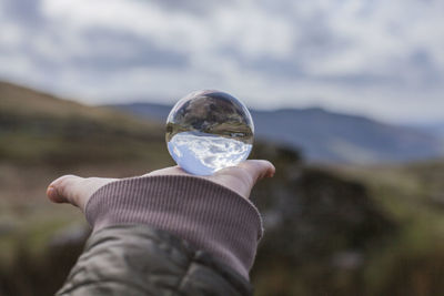 Midsection of person holding glass against blurred background