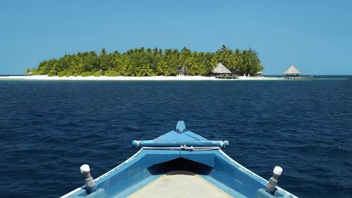 Boat sailing in sea against clear blue sky