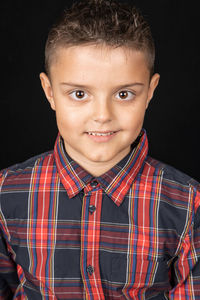 Portrait of smiling boy against black background