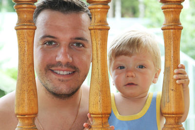 Close-up portrait of smiling father and son looking through railing