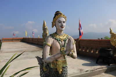 Statue against temple and building against sky