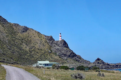 Scenic view of road by mountain against clear blue sky