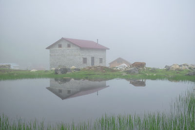 Houses by lake against clear sky