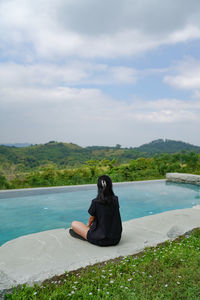 Woman sitting on shore against sky